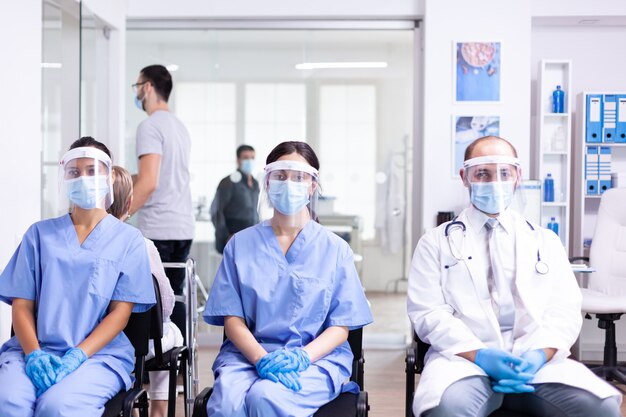 병원 대기실에서 코로나바이러스 발생에 대한 안전 예방책으로 흰색 코트와 얼굴 마스크를 쓴 간호사와 의사
