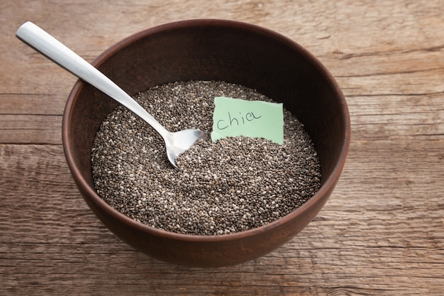 Nutritious chia seeds in a bowl on wooden background.