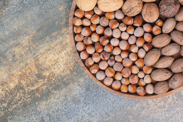 Nutritious mixed brown nuts on wooden bowl. High quality photo