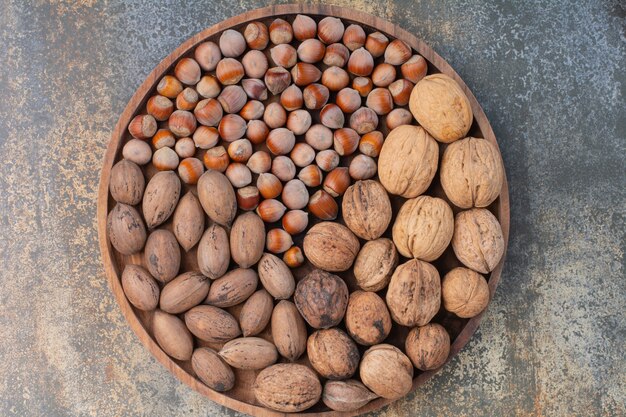 Питательные смешанные коричневые орехи на деревянной миске. Фото высокого качества