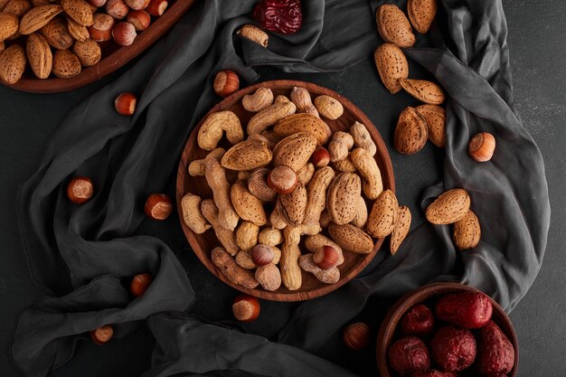 Nuts and almond shells in a wooden plate with dry fruits around. 