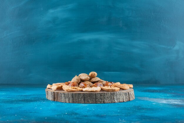 Nuts and dried fruits on a board on the blue surface