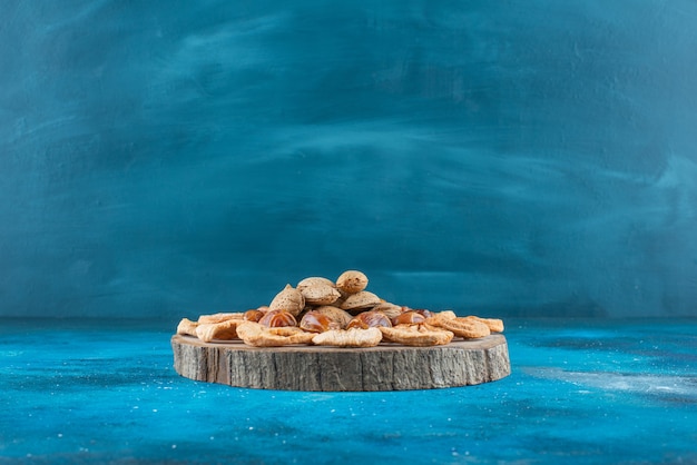 Nuts and dried fruits on a board on the blue surface