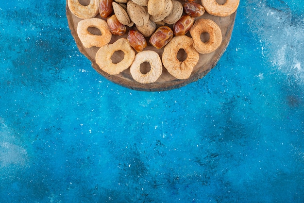 Nuts and dried fruits on a board , on the blue table.