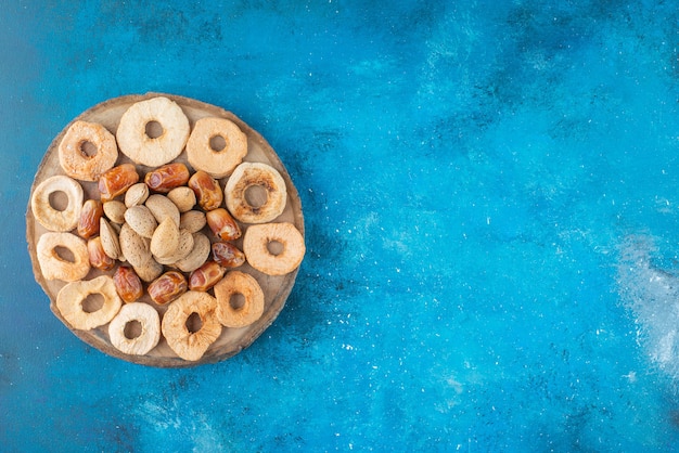 Nuts and dried fruits on a board , on the blue table. 