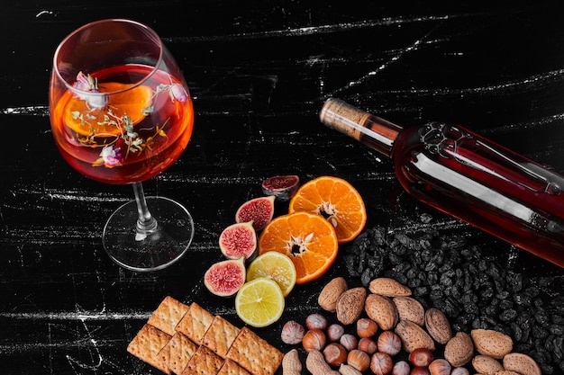 Nuts and fruits on black background with wine.