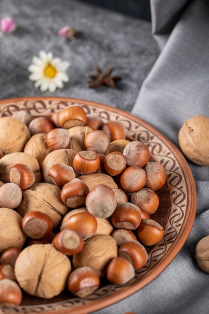 Nuts and walnuts in a pottery bowl and on the tablecloth with daisies around