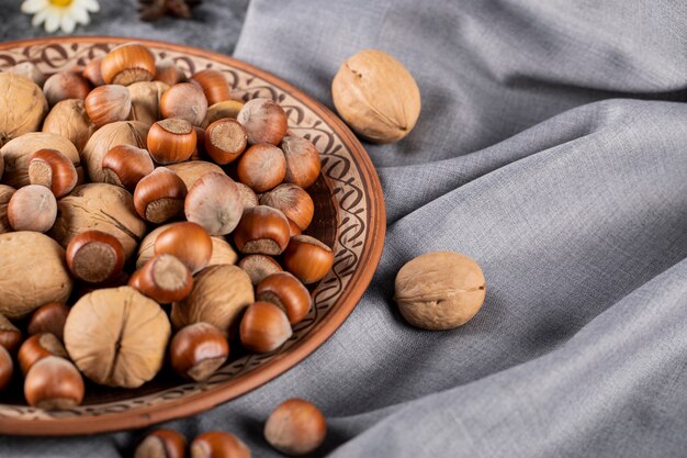 Nuts and walnuts in a pottery bowl and on the tablecloth