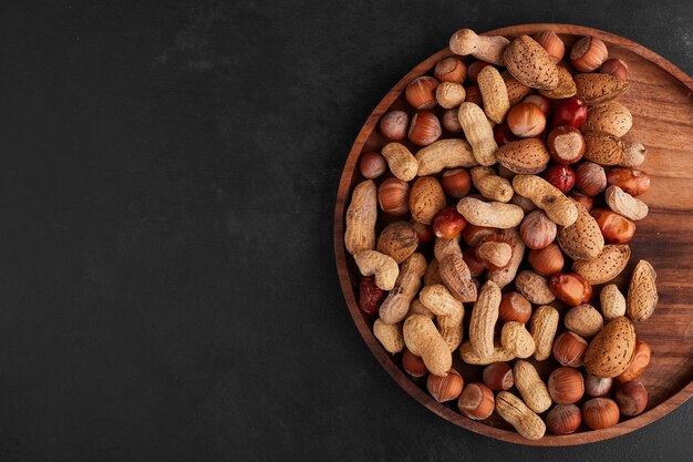 Free photo nuts in a wooden platter, top view.