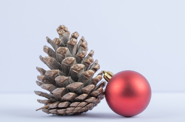 Foto gratuita un cono di quercia con palline rosse scintillanti su fondo bianco