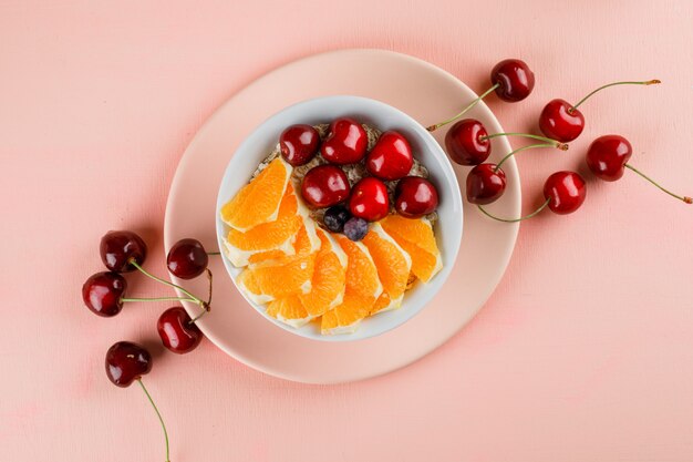 Oat flakes in a bowl with cherry, orange, berries