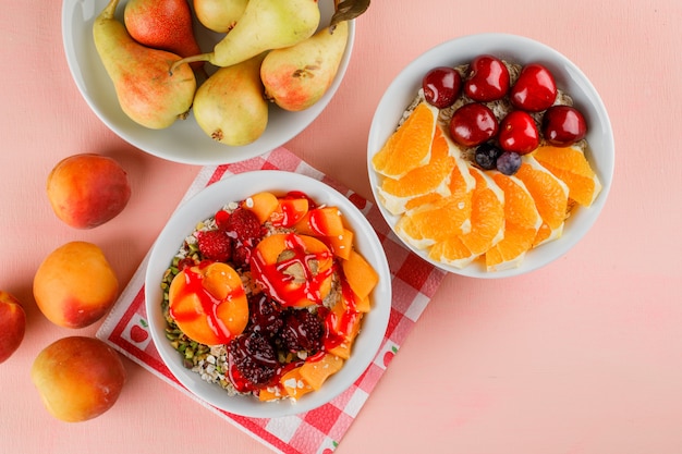 Oat flakes in bowls with nuts, apricot, berries, pear, cherry, orange