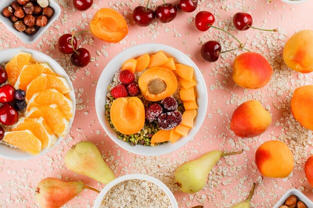 Oat flakes in bowls with pear, orange, cherry, apricot, nuts