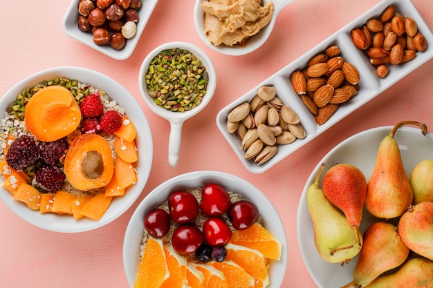 Oat flakes with fruits, nuts, peanut butter in bowls