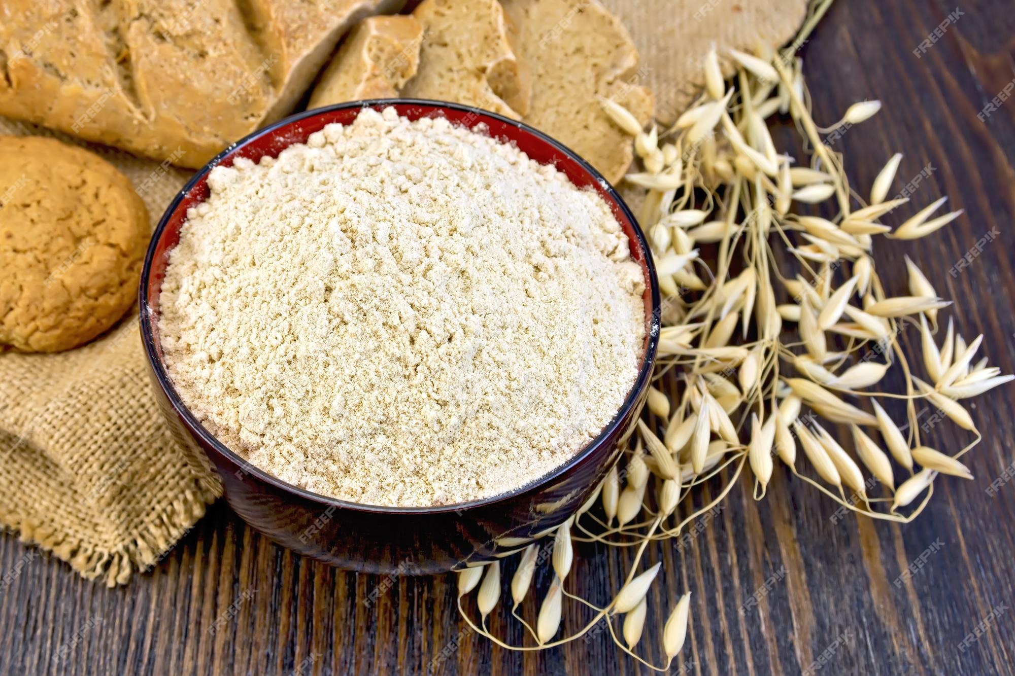 Premium Photo | Oat flour in a bowl cookies and bread made from oatmeal on  sackcloth stalks of oats on the background of wooden boards