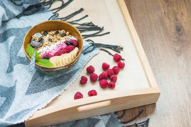 Oatmeal bowl with raspberries on wooden tray