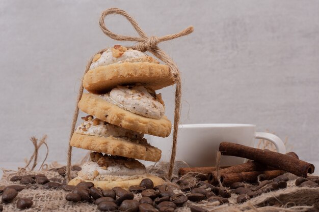 Foto gratuita biscotto di farina d'avena, tazza di tè, cannella e chicchi di caffè su tela.