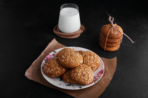 Oatmeal cookies with black cumin and a cup of milk aside. 