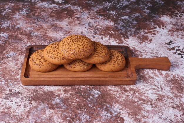 Free photo oatmeal cookies with black cumin on a wooden platter, angle view.