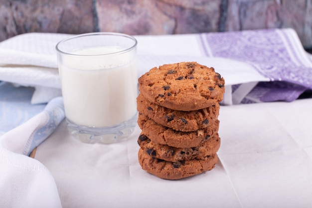 Oatmeal cookies with a glass of milk on white tablecloth