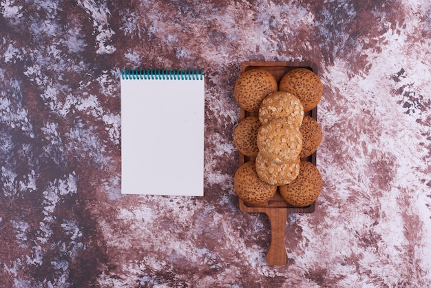 Foto gratuita biscotti di farina d'avena su un piatto di legno con un notebok da parte.