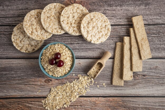 Oatmeal crackers, grains with berries and a cup of milk on the table, top view