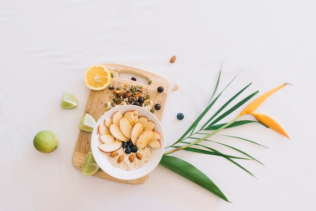 Free photo oatmeal decorated with apple slice and dryfruits on wooden chopping board