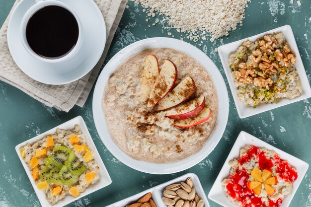 Oatmeal in plates with fruits, jam, nuts, cinnamon, coffee, oat flakes