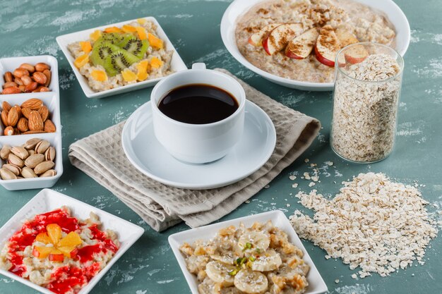 Oatmeal in plates with fruits, jam, nuts, cinnamon, coffee, oat flakes