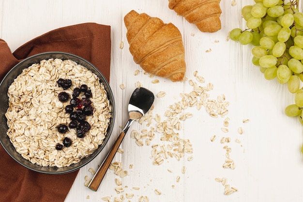Oatmeal porridge bowl with grapes and croissants