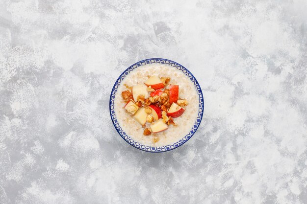 Oatmeal porridge in a bowl with honey and red apple slices,top view