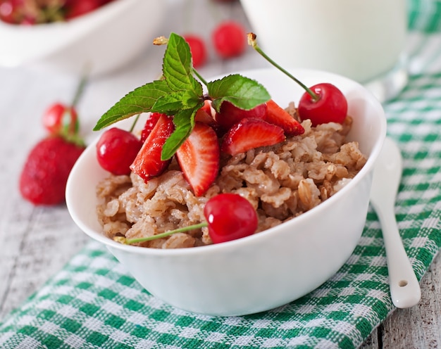 Oatmeal porridge with berries in a white bowl