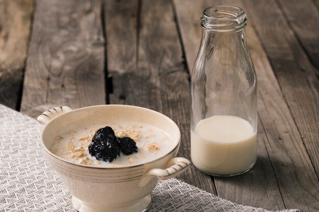 Oatmeal porridge with bottle of milk on the rustic table