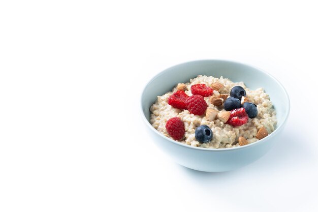 Oatmeal porridge with raspberries blueberries and almonds in bowl isolated on white background