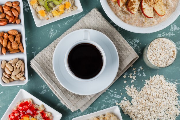 Oatmeal with fruits, jam, nuts, cinnamon, coffee, oat flakes in plates