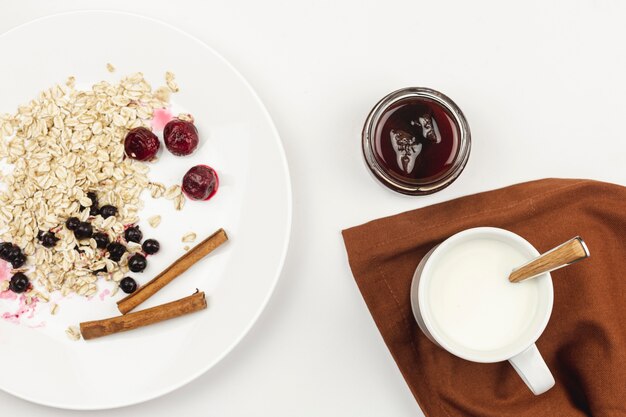 Foto gratuita farina d'avena con marmellata e bastoncini di cannella su un piatto bianco