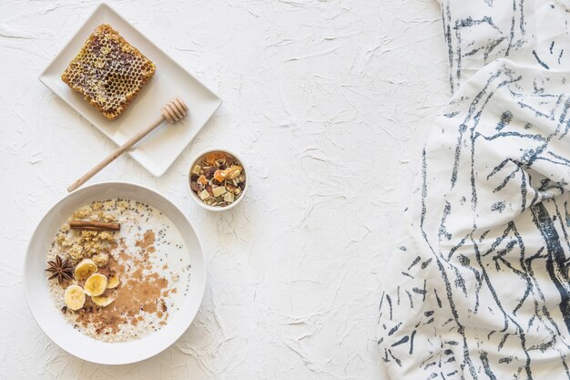 Foto gratuita oatmeals; dryfruits e favo con sciarpa su fondo strutturato