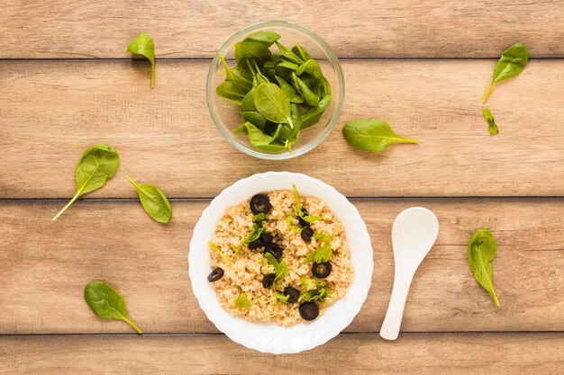 Oats garnished with basil leaf and olive for breakfast in bowl