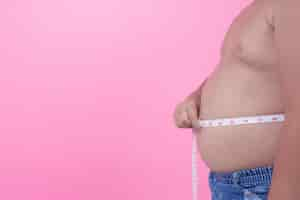 Free photo obese boy who is overweight on a pink background.