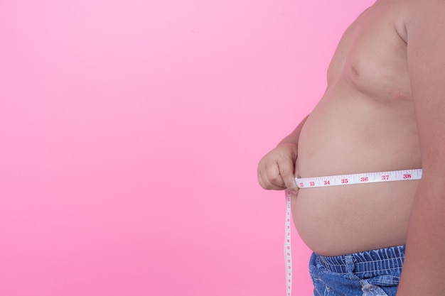 Obese boy who is overweight on a pink background.