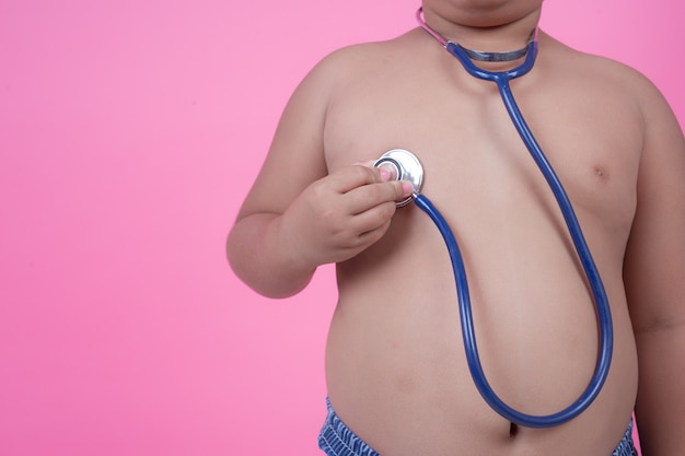 Obese boy who is overweight on a pink background.