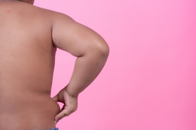 Free photo obese boy who is overweight on a pink background.