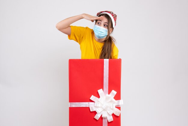 화이트에 큰 크리스마스 선물 뒤에 산타 모자 서 관찰 소녀