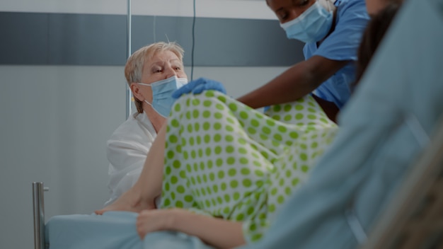無料写真 病棟のベッドで白人女性のために赤ちゃんを出産する産科医。出産のスペシャリストを支援するアフリカ系アメリカ人の看護師。多民族の人々と出産する若い患者