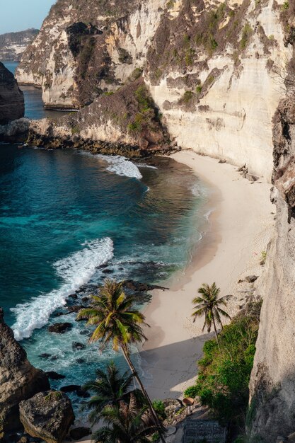 Ocean hitting the sandy beach surrounded by cliffs