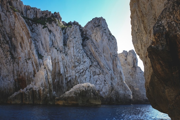 Ocean surrounded by the rocky cliffs gleaming under the blue sky - great for wallpapers