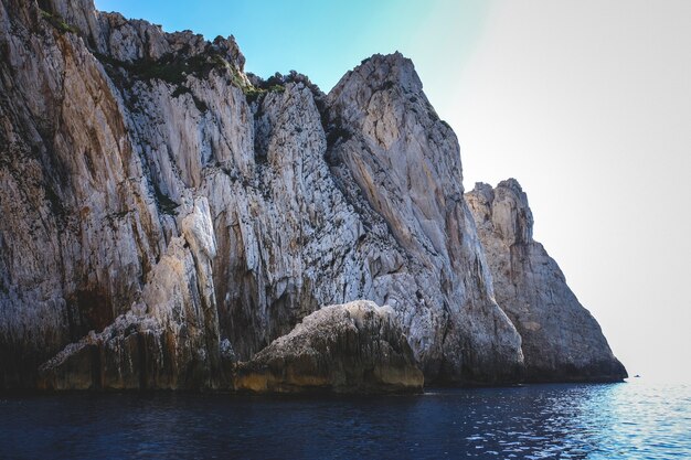 Ocean surrounded by the rocky cliffs gleaming under the blue sky