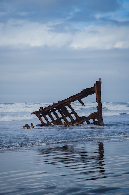 ocean waves splashing to an abandoned piece of wood under the cloudy sky