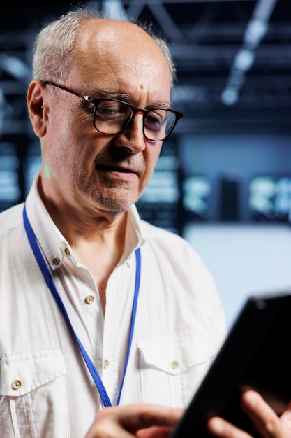 Octogenarian engineer in crypto mining farm with specialized server racks using Blockchain technology. Fintech expert inspecting asic racks solving complex computational operations in data center