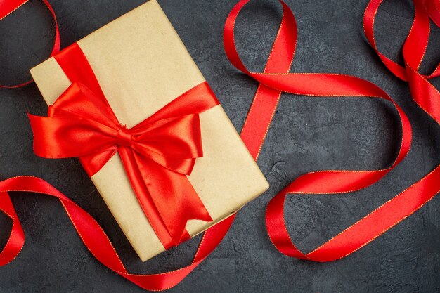 Oerhead view of stacked beautiful gift with red ribbon on dark background